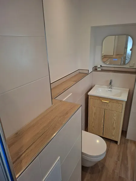 Von SHK Schlösser saniertes Bad mit Hänge-WC, Waschtisch mit Holzunterschrank und Fliesen in Holzoptik